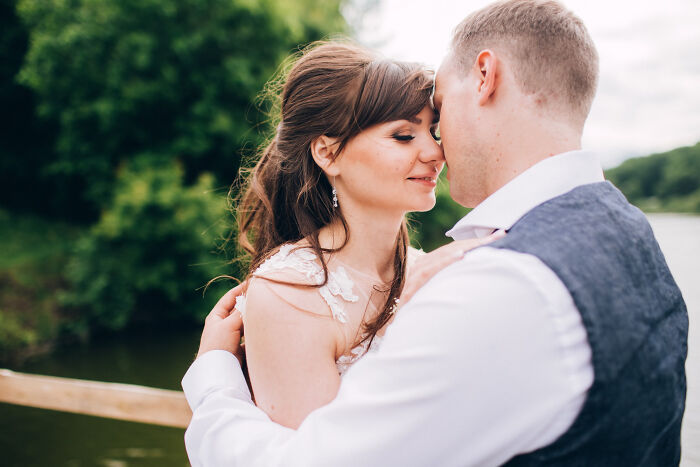 A couple embracing outdoors near a lake, highlighting childhood norms people grew up to realize were weird.