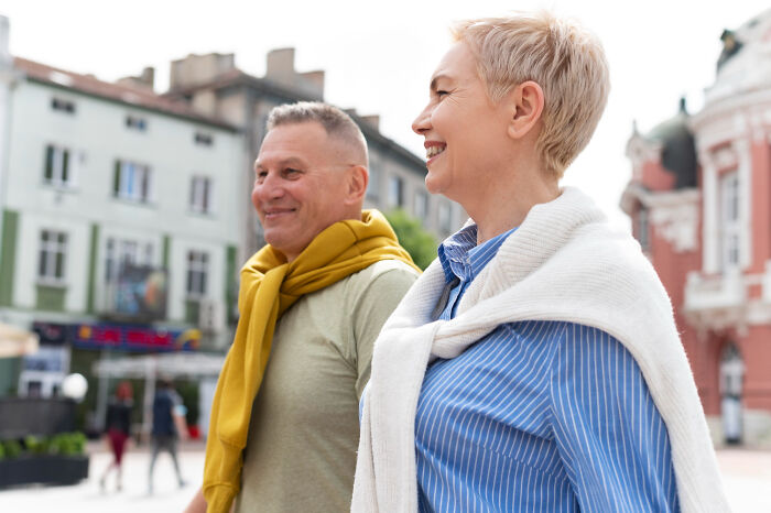 Middle-aged couple smiling and walking outdoors, reflecting on childhood norms they grew up to realize were weird.
