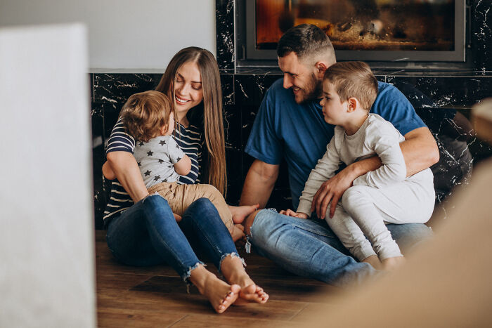 Family sitting on the floor playing and laughing together, highlighting childhood norms that seem unusual in hindsight.
