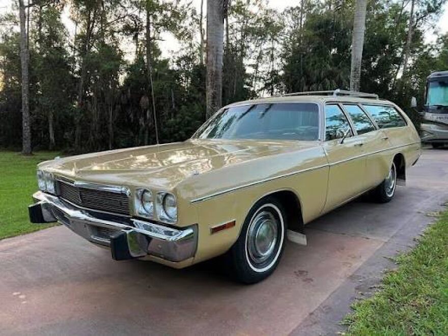 A vintage tan station wagon, a classic car that makes people take a trip down memory lane, parked on a driveway.