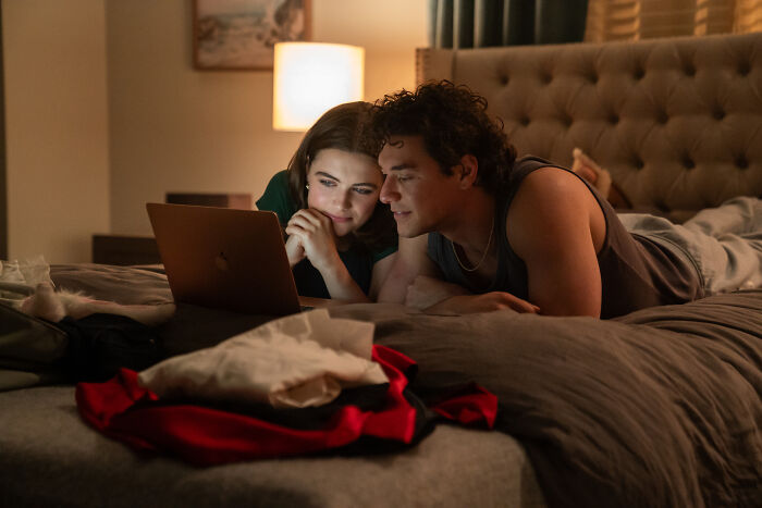 A couple lies in bed, looking at a laptop. The new romance film is reckless and needs a trigger warning.