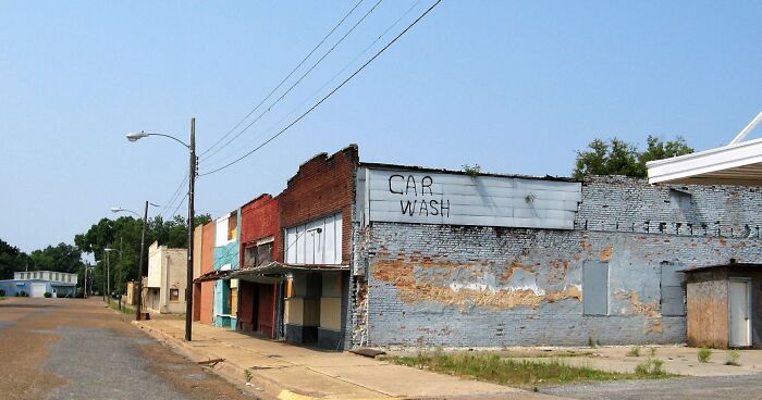 Deserted street with rundown buildings and an old car wash sign, depicting some of the worst places in the US visited.