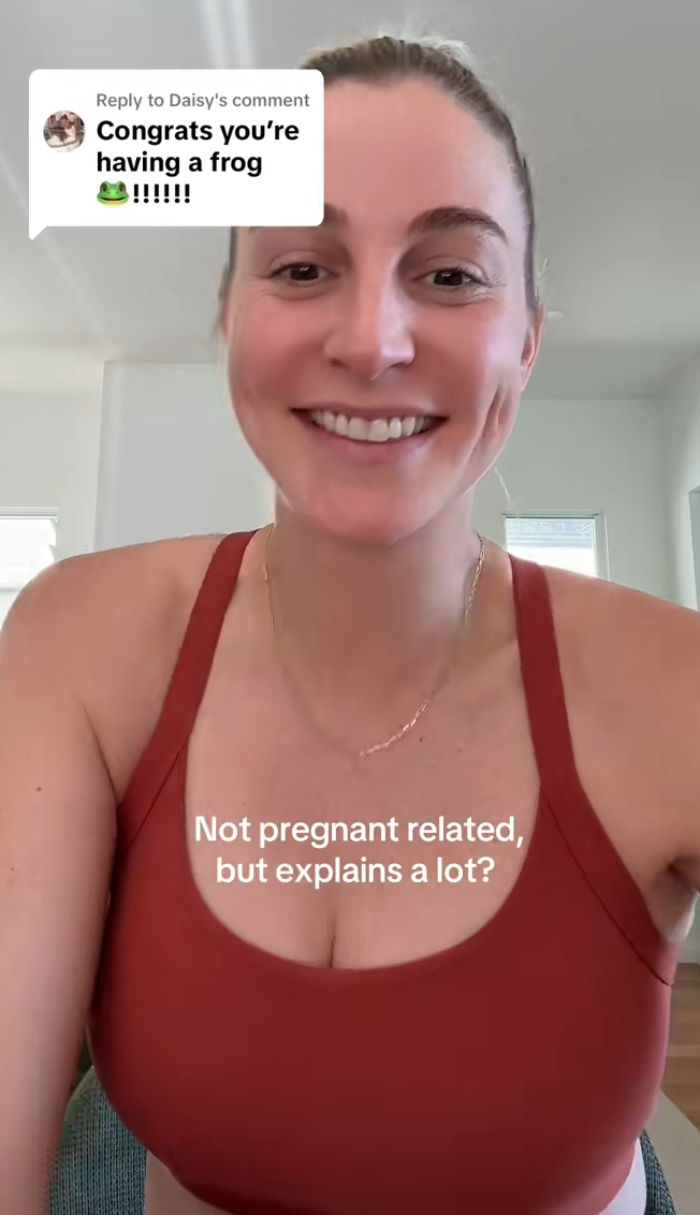 Mulher sorridente compartilha sintomas bizarros de gravidez em uma regata vermelha casual, provocando reação de internautas em uma sala iluminada. Mulher sorridente compartilha sintomas bizarros de gravidez em uma regata vermelha casual, provocando reação de internautas em uma sala iluminada.