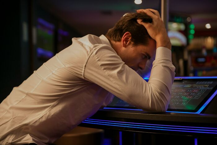 Man looking stressed and frustrated at a gaming machine, reflecting on experiences with former bullies and childhood cruelty.