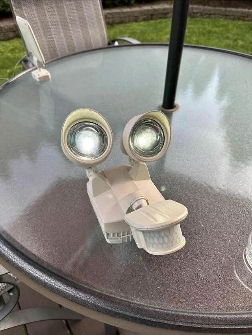 Outdoor light fixture on glass table resembling a smiling face, an example of pareidolia captured in a photo.