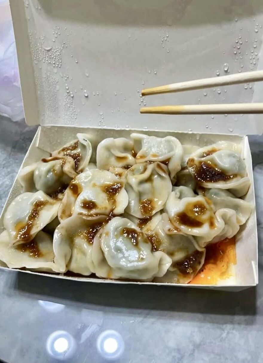 Box of dumplings with sauce spots resembling faces, showcasing pareidolia in everyday food photography.