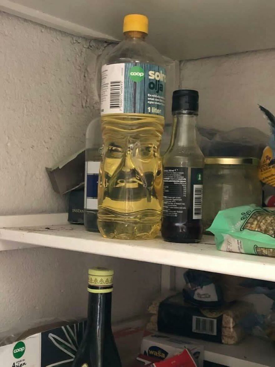 Plastic bottle with oil on a shelf showing pareidolia with facial features appearing in the liquid inside.