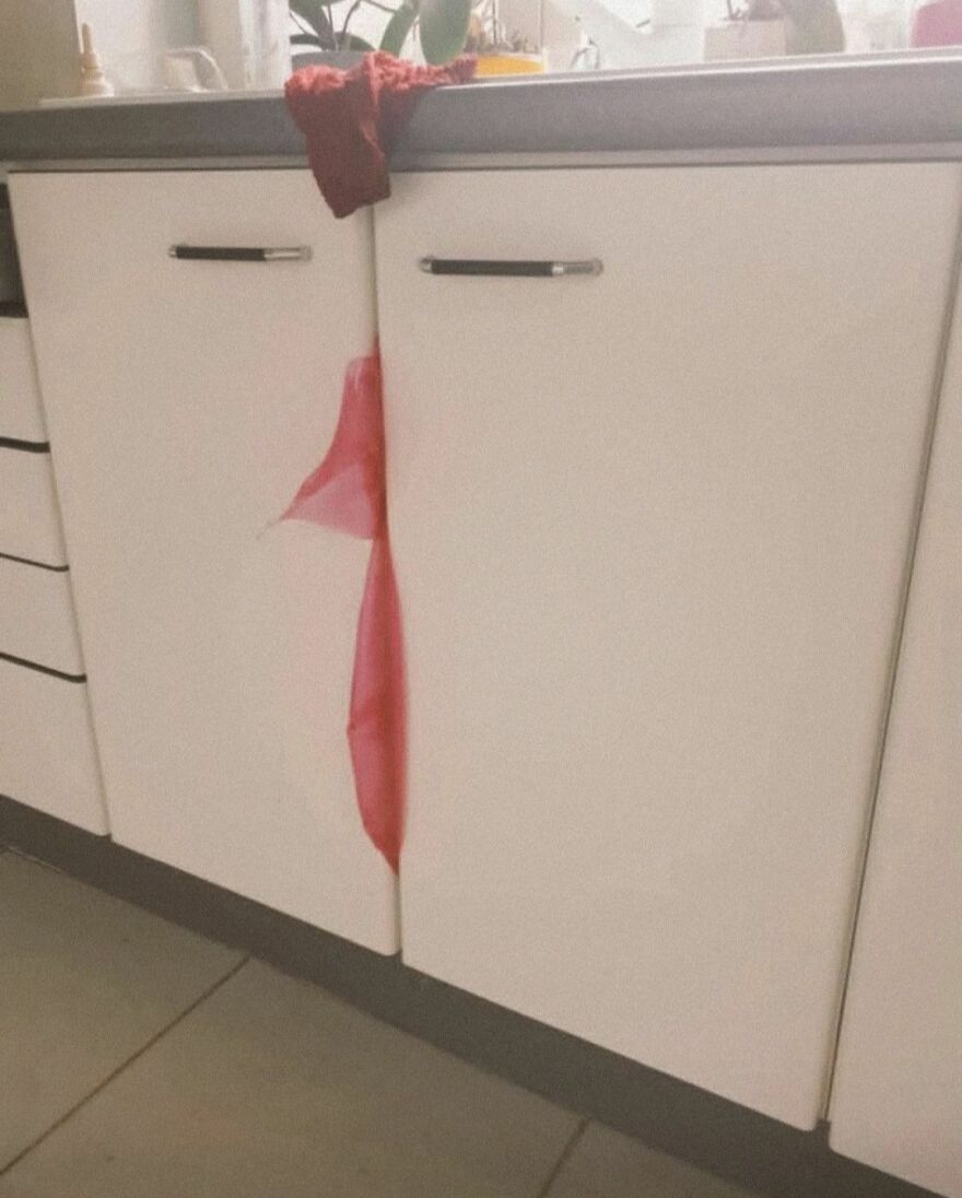 Kitchen cabinet doors with a red cloth creating pareidolia, resembling a hidden figure in an everyday setting.