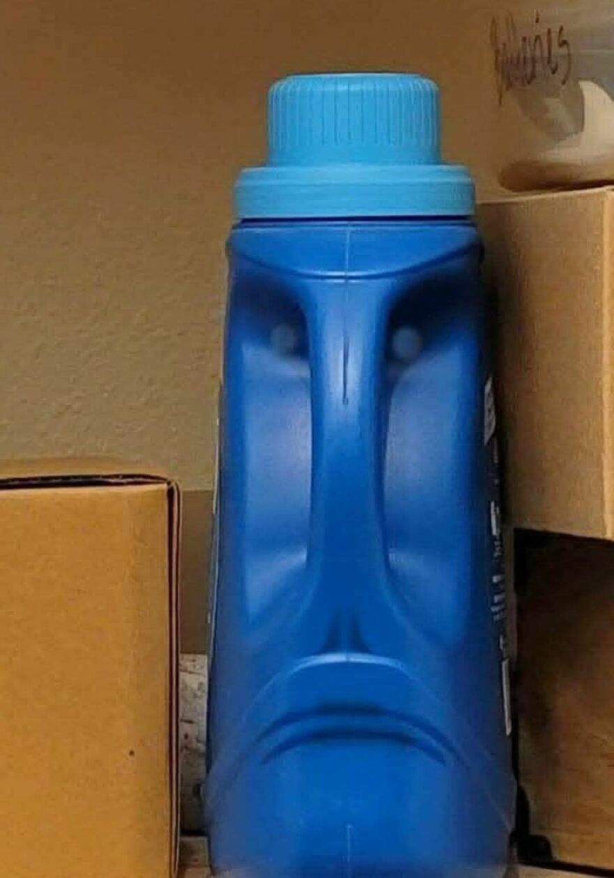 Blue plastic bottle with a cap resembling a sad human face, showcasing pareidolia in an everyday object photograph.