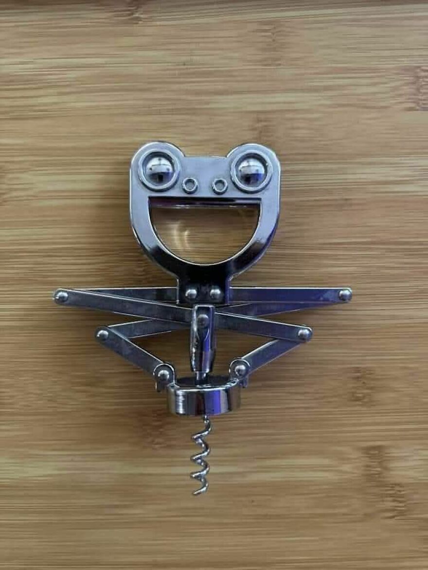 Metal corkscrew on wooden surface resembling a smiling face, an example of pareidolia captured in a photo.