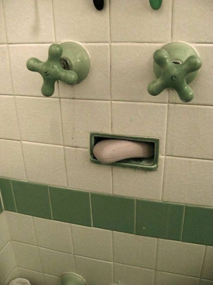Bathroom wall with green handles and soap holder creating a face illusion, an example of pareidolia in everyday objects.