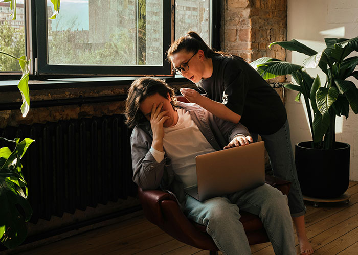A distressed person covers their face while another talks to them, symbolizing the need for better friends.
