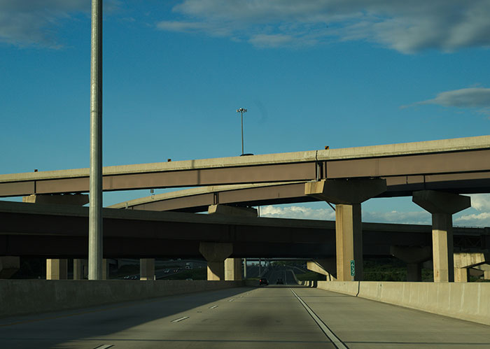 A multi-level highway interchange with concrete pillars and overpasses under a bright blue sky, illustrating complex friendships.