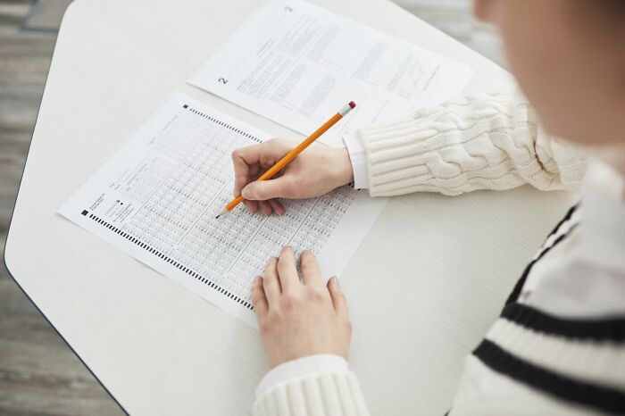 Person wearing a white sweater filling out a form with a pencil, related to weird and interesting medical facts.