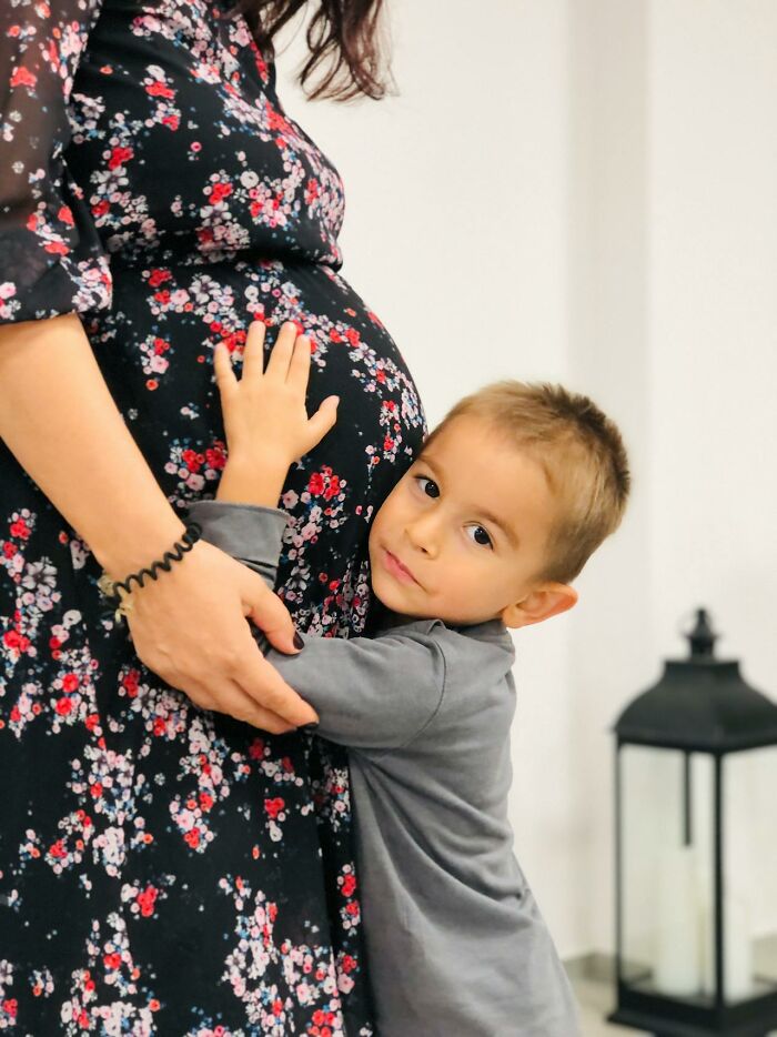 Young boy hugging pregnant mom wearing floral dress, capturing touching moments in amazing stories about moms.