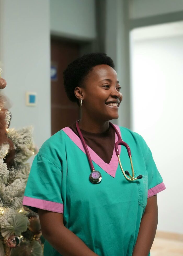 Smiling nurse in green scrubs with stethoscope, representing caring moms and inspiring stories about motherhood.