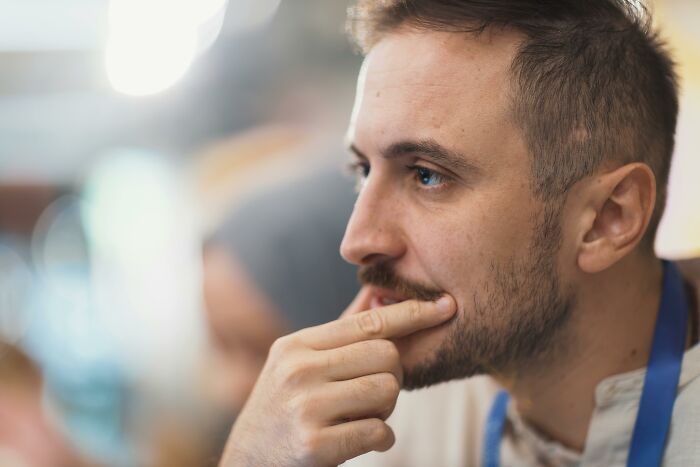 A man with a beard and mustache ponders, finger on his lip. He considers family secrets.
