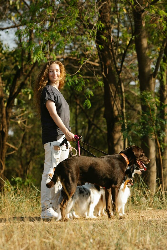 Woman walking dogs outdoors in a forest setting, representing loving moments shared with moms in everyday life.