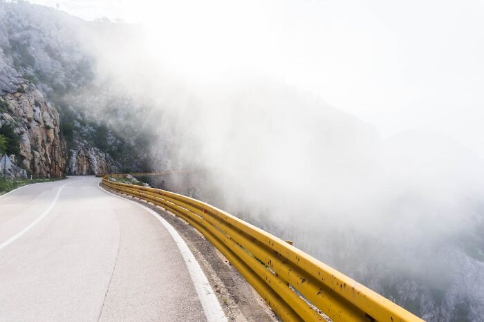 Mountain road with yellow guardrail disappearing into fog, evoking a wild and unpredictable bachelor party vibe.
