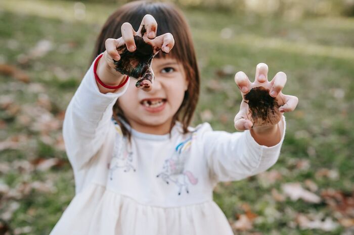 Child playing outdoors showing dirty hands with mud, illustrating parenting tips and tricks shared by parents.