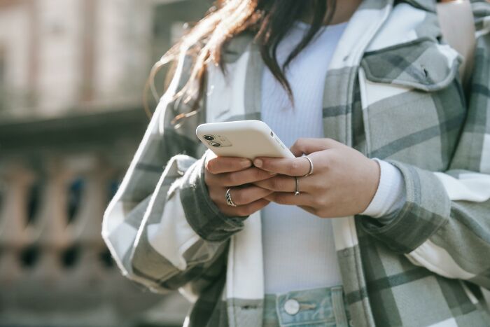 Person wearing a plaid jacket holding a smartphone, illustrating horrendous things committed by best friends concept.
