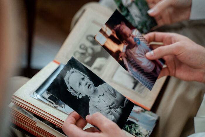 Hands hold old family photos and a photo album, reflecting on family secrets and past memories.