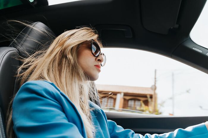 Woman wearing sunglasses driving a car, reflecting on intuition being proved right in a thoughtful moment.