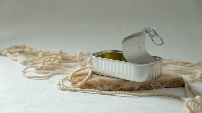 Open empty metal can with string and fabric on a light surface representing unusual items TSA has confiscated.