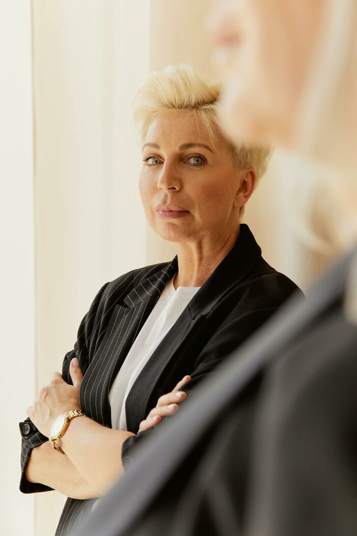 Confident woman with short blonde hair standing with arms crossed, reflecting on inspiring stories about moms.