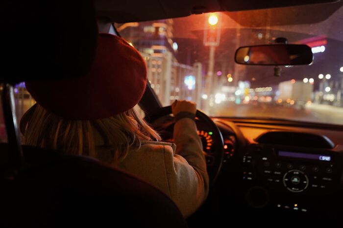Person driving at night, experiencing a moment of intuition being proved right in a city setting.