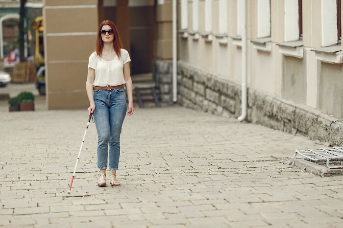 Woman with visual impairment walking confidently with a white cane on a city street, illustrating medical facts about blindness.