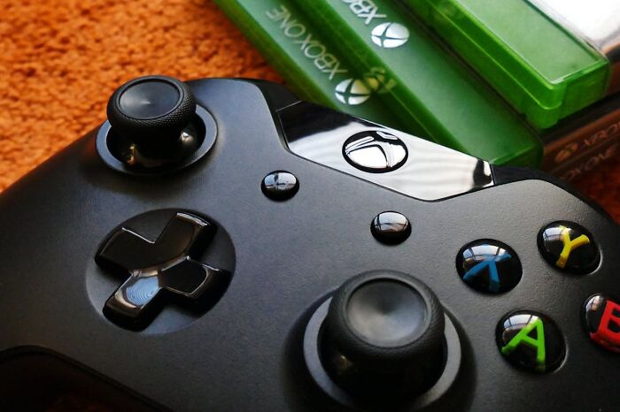 Black Xbox controller with two green Xbox game cases on an orange surface, illustrating PR mistakes in company marketing.