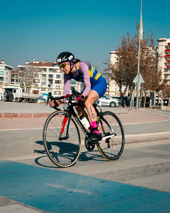 Woman cyclist participating in a race, showcasing determination and strength in an outdoor urban setting.