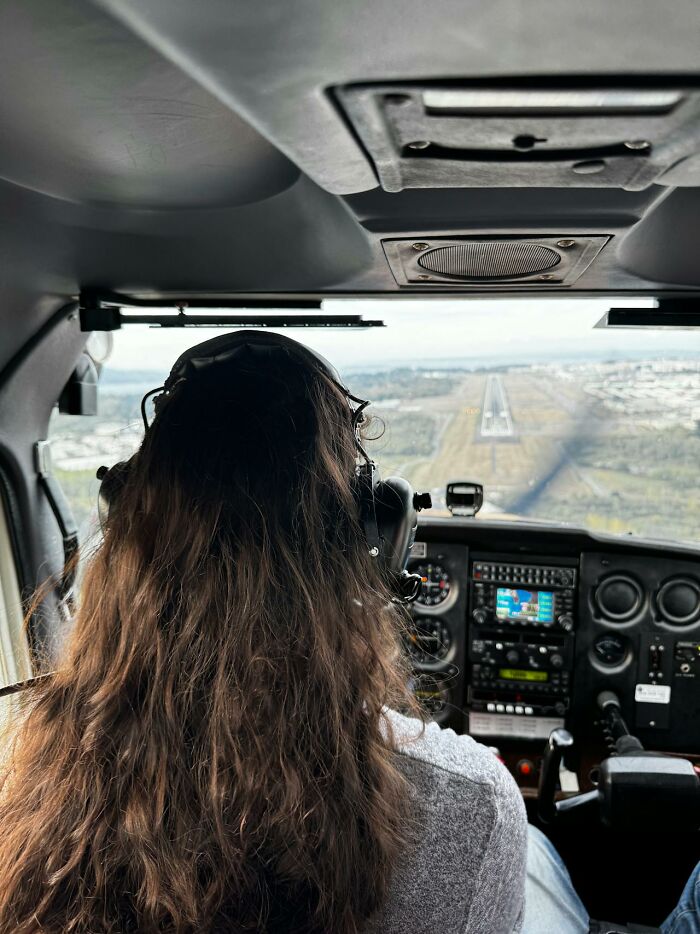 Woman with long hair piloting a small plane landing, illustrating inspiring and interesting stories about their moms.
