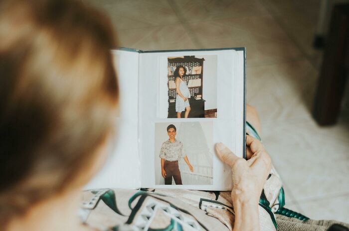 An older person looking at a photo album, reminiscing about family secrets and past memories.