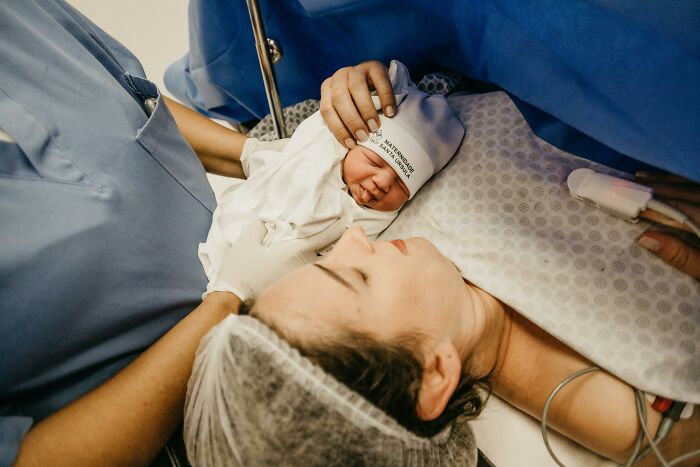 Newborn baby in a hospital hat resting on mother's chest, a disturbing sound from a recent childbirth.