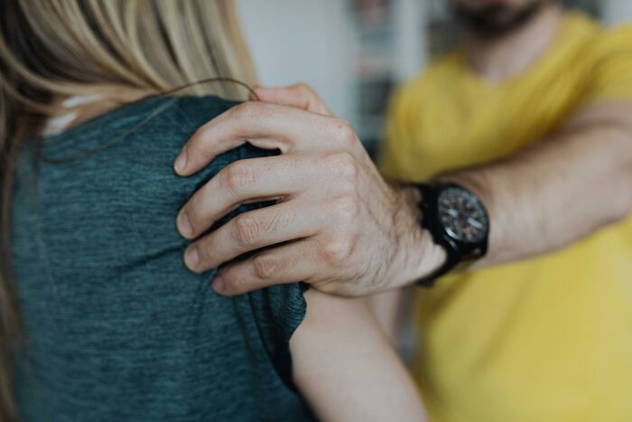 A man's hand with a watch on his wrist comforting a woman's shoulder; represents the emotional impact of disturbing sounds.