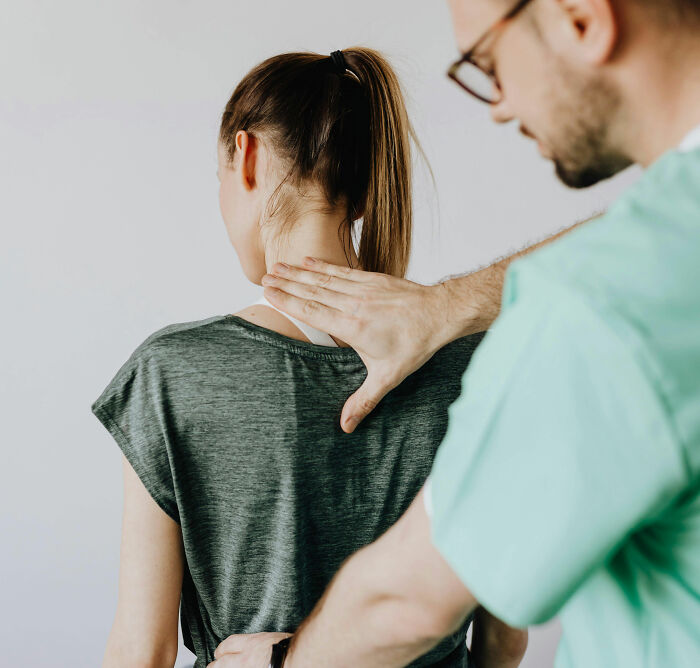 Doctor examining a woman’s upper back, focusing on a potential buffalo hump that could indicate serious health issues. Doctor examining a woman’s upper back, focusing on a potential buffalo hump that could indicate serious health issues.