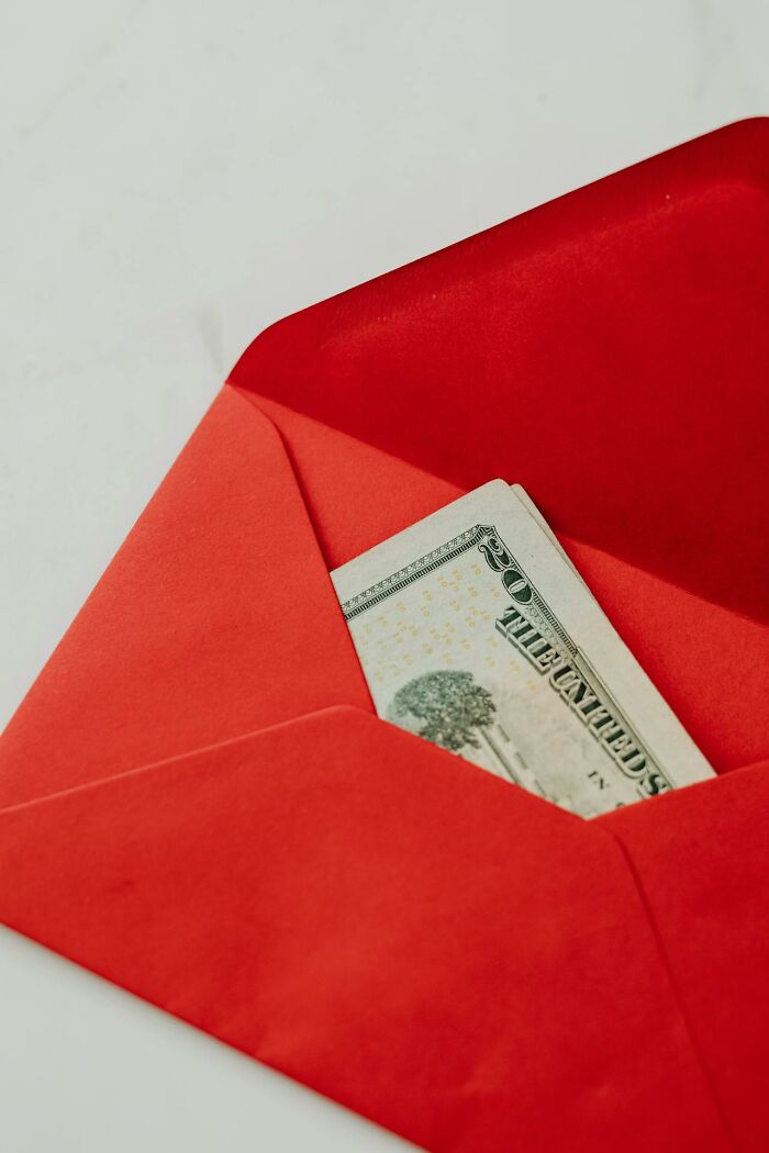 Red envelope with US dollar bills inside, symbolizing employee decisions to quit work immediately and leave jobs.