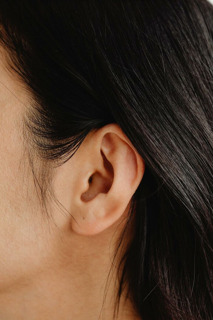Close-up of a human ear with dark hair, illustrating one of the weird and interesting medical facts.