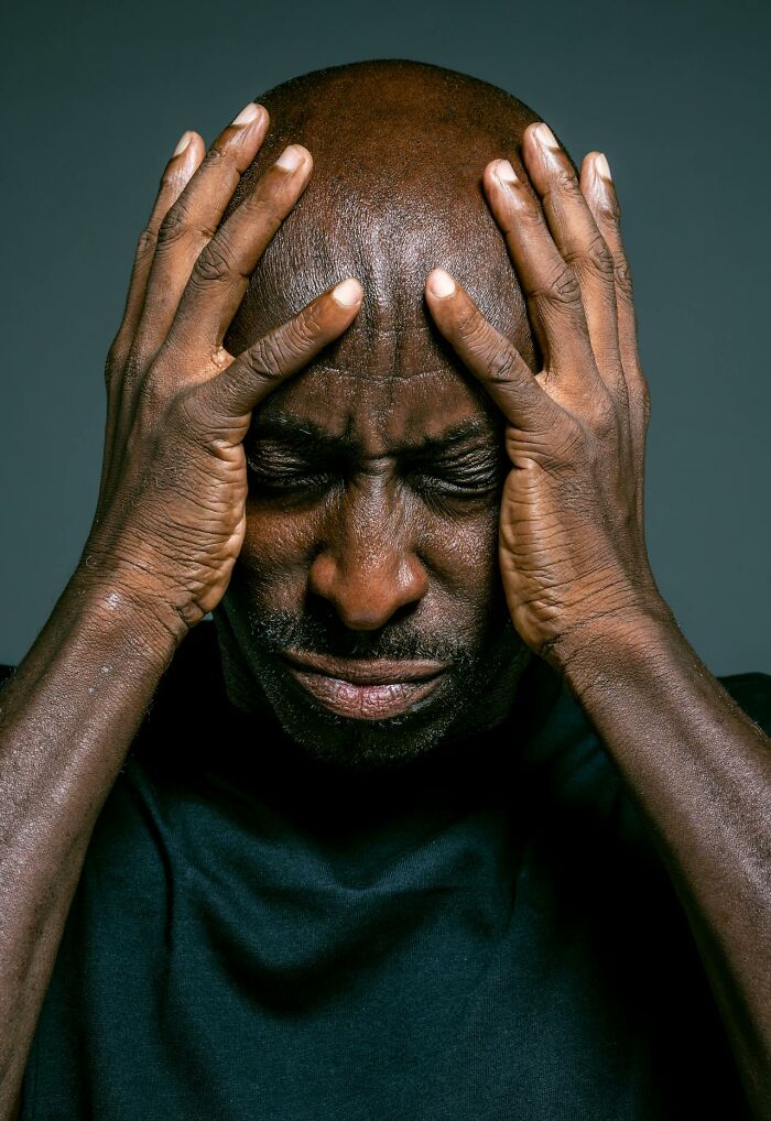 Man holding his head with eyes closed, appearing stressed and worried, illustrating terrifying statistics impact.
