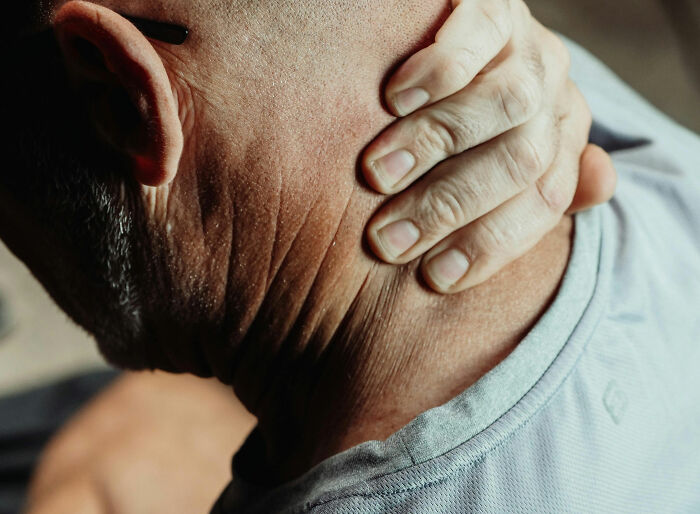 Close-up of a person holding the back of their neck showing signs of buffalo hump that could indicate serious health issues. Close-up of a person holding the back of their neck showing signs of buffalo hump that could indicate serious health issues.