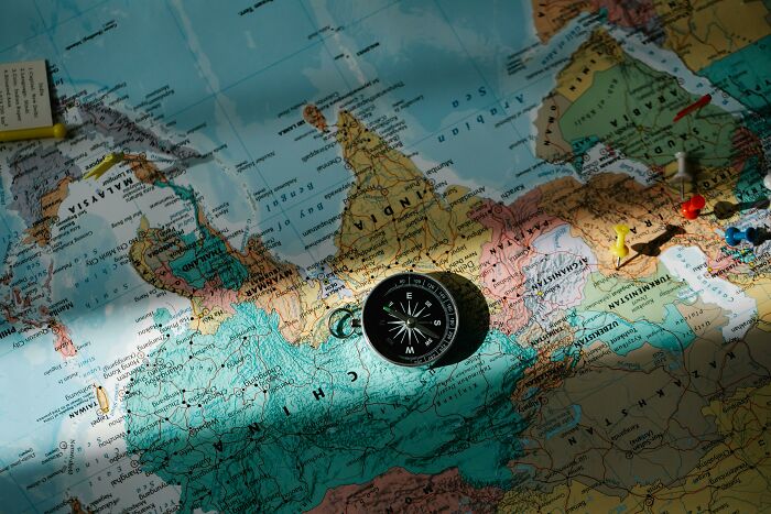 A compass on a world map with pushpins, ready to prove your map skills in a geography quiz.