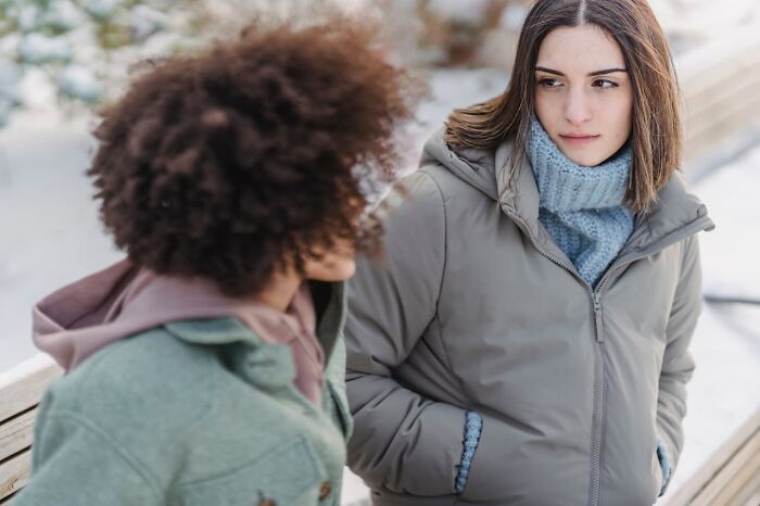 Two women outdoors in winter coats, one looking thoughtfully at the other, illustrating intuition being proved right.