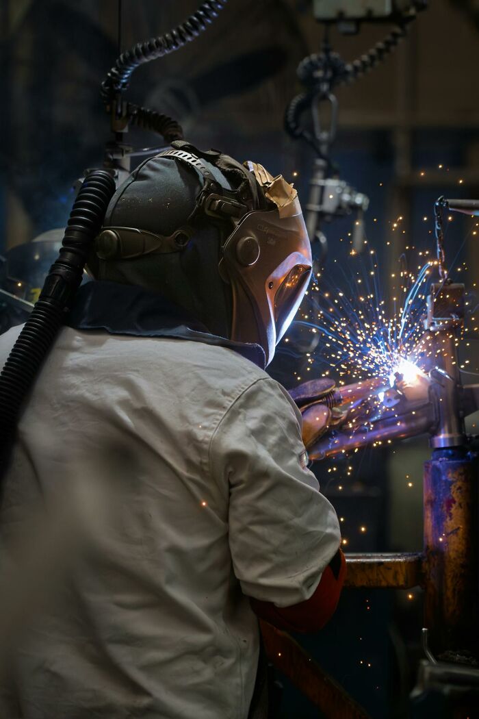 Worker welding metal with protective gear, illustrating wild times employees decided to quit this job immediately.