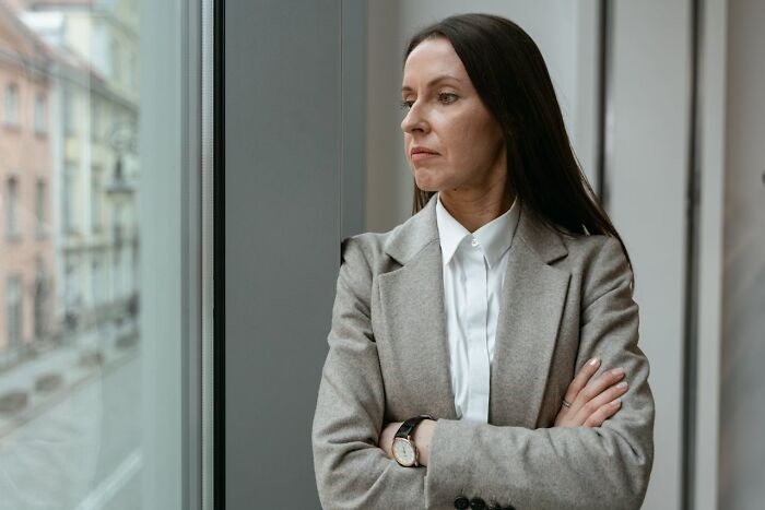 Woman in a gray blazer looking out the window, reflecting on wild times employees deciding to quit their job immediately.
