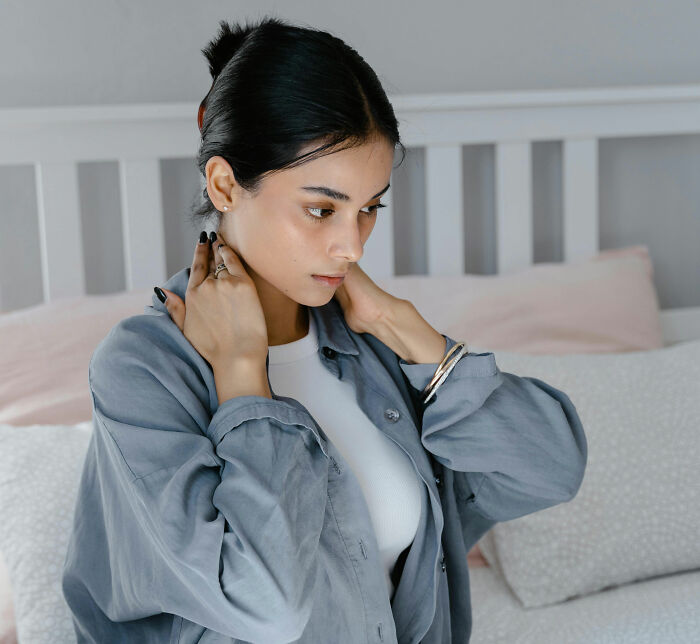 Young woman touching neck and upper back, concerned about buffalo hump symptoms and possible health issues at home. Young woman touching neck and upper back, concerned about buffalo hump symptoms and possible health issues at home.
