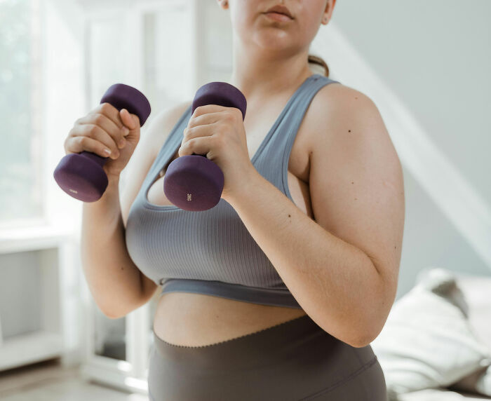 Woman in workout clothes holding purple dumbbells, highlighting concerns about buffalo hump and related health issues. Woman in workout clothes holding purple dumbbells, highlighting concerns about buffalo hump and related health issues.