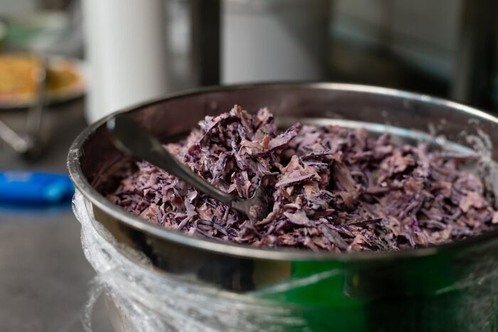 Bowl of shredded purple cabbage salad with a serving spoon in a kitchen setting, illustrating wild times employees quitting jobs.