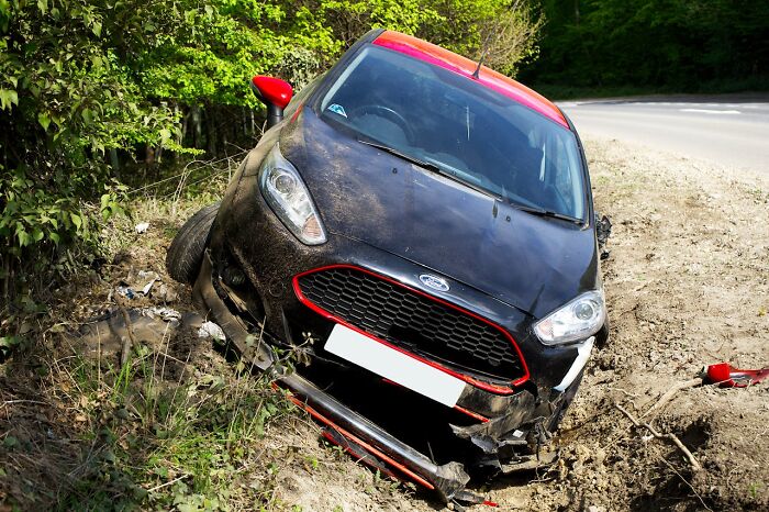 Black and red car crashed off road into dirt ditch, illustrating stories about people seeing their intuition proved right.